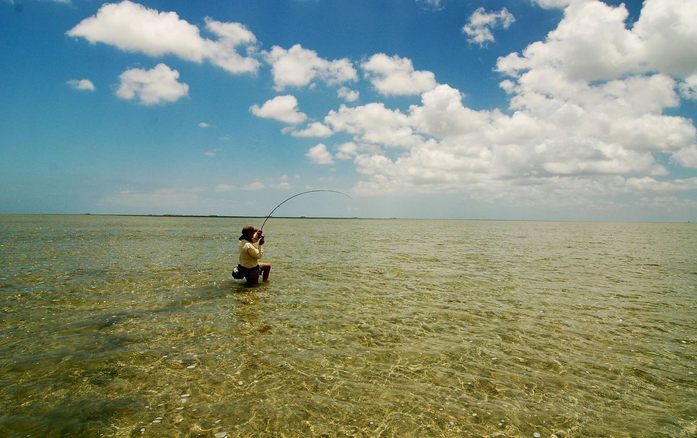 Fly angler wading the clear flats under South Texas clouds