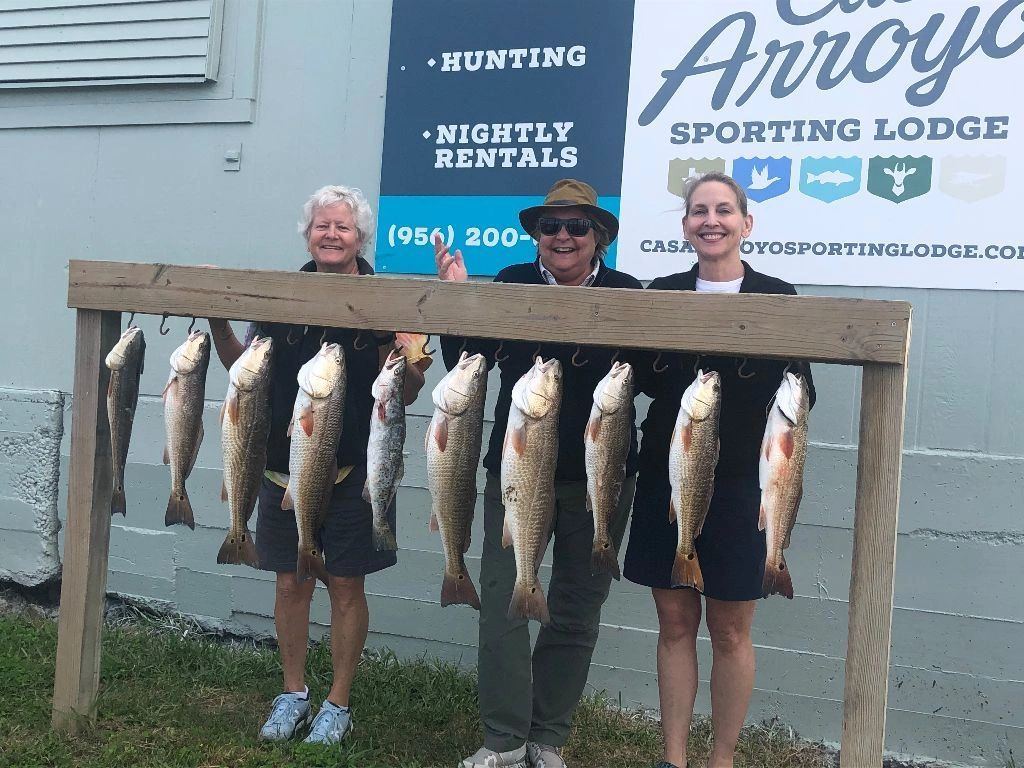 Three anglers with a rack of redfish at the lodge